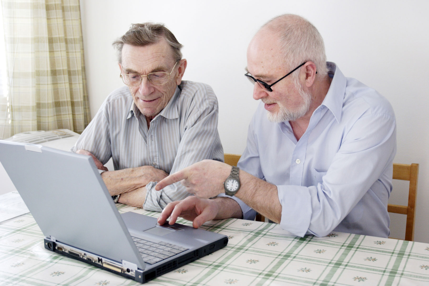 To menn sitter foran en PC. En av dem peker på skjermen. Foto: Mostphotos.