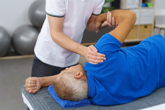 En fysioterapeut eller manuellterapeut jobber med skulderen til en pasient. Foto: Mostphotos.