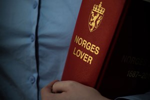 En person holder Norges lover under armen. Foto: Ådne Sinnes.