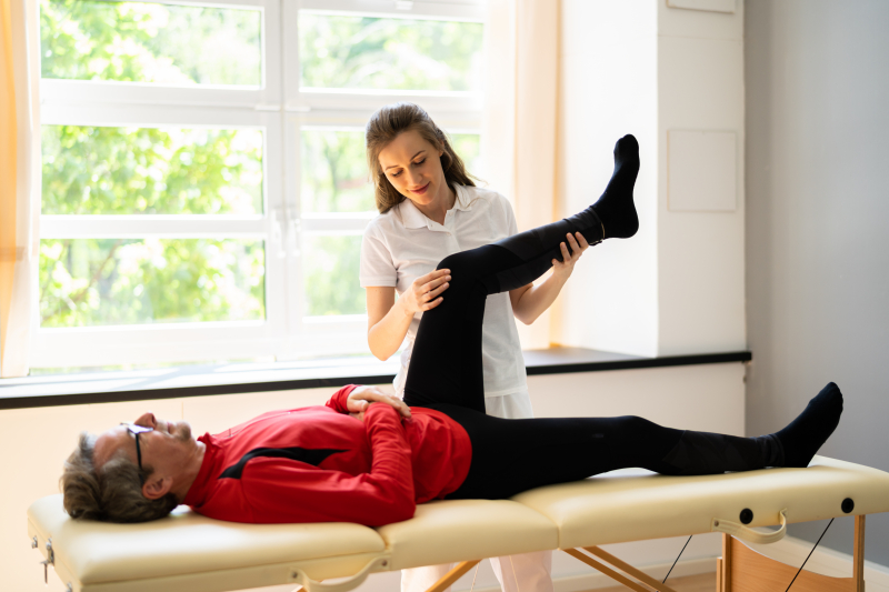 En fysioterapeut som hjelper en pasient med foten/kneet. Foto: Mostphotos.
