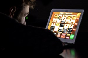 Illustrasjonsbildet syner ein mann som sit framfor ein PC-skjerm og speler eit pengespel.